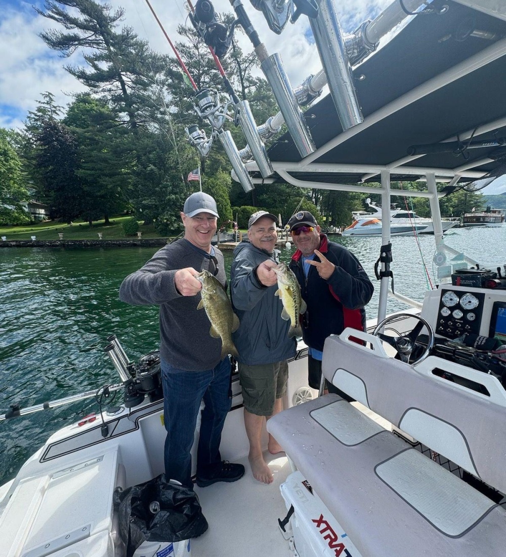 Three male VCS Engineering employee's showing off the fish they just caught on a team building excursion.