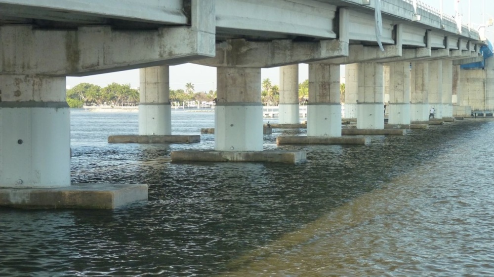 Concrete Piles under a large bridge. The bottom of the Piles feature a white PVC Jacket which protects the concrete pile from chloride exposure.